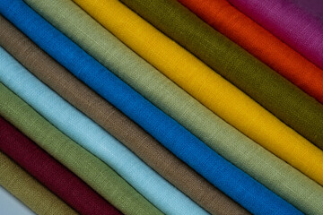 A stack of multi-colored bright linen fabric, close-up. Linen background. Fabric stripes