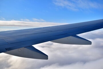 Fototapeta na wymiar Wing of airplane. Wing of a passenger plane on background of blue sky above white fluffy clouds