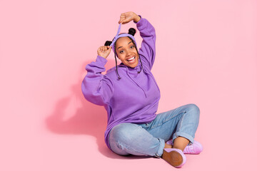 Photo of attractive funny african lady dressed violet sweatshirt buns smiling adjusting headband isolated pink color background