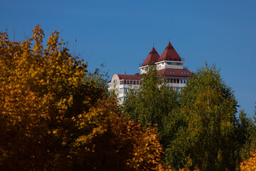 Autumn view, city park and buildings. Yellow and orange trees, blue skies and a recreation...