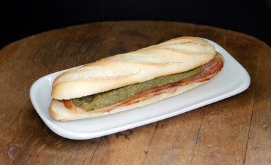 bocadillo de panceta con pimiento verde en plato blanco