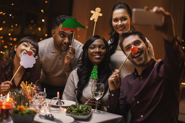 holidays, people and celebration concept - multiethnic group of happy friends with party props...