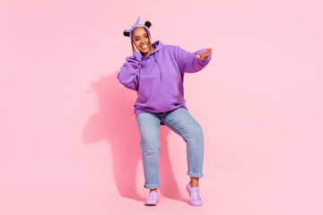 Photo of funny beautiful african lady dressed violet sweatshirt buns smiling dancing isolated pink color background