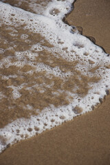 The wave crashed on the sandy beach. Wave foam. Beach landscape. Nature backgrounds