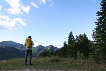 Fototapeta na wymiar Tourist with backpack enjoying mountain landscape, back view. Space for text