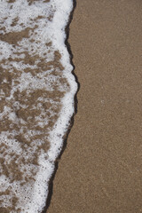 The wave crashed on the sandy beach. Wave foam. Beach landscape. Nature backgrounds