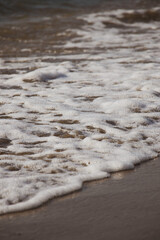 The wave crashed on the sandy beach. Wave foam. Beach landscape. Nature backgrounds