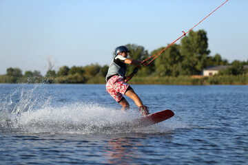 Teenage boy wakeboarding on river. Extreme water sport