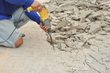 hand holding Jackhammer to break concrete on ground,selective focus