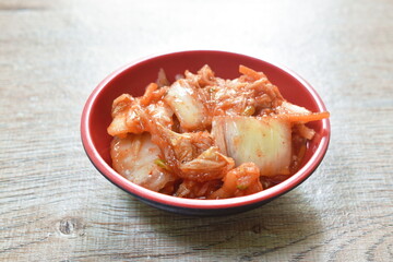 Kimchi pickled cabbage and carrot with sesame Korean salad in red cup on table

