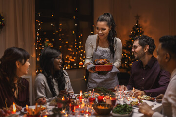holidays and celebration concept - multiethnic group of happy friends having christmas dinner at...