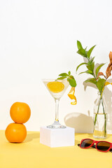  DRINK WITH ORANGE, A COCKTAIL GLASS TWO STACKED ORANGES A SUNGLASSES AND A NATURAL ARRANGEMENT IN A BOTTLE 