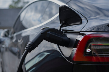 Close up of a plug connected to electric hybrid car charger. Green transportation, no emission, new technology concept.
