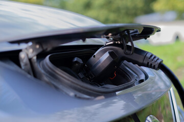 Close up of a plug connected to electric hybrid car charger. Green transportation, no emission, new technology concept.