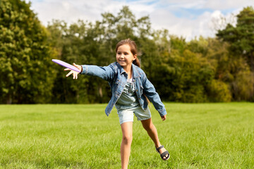 childhood, leisure and people concept - happy girl playing game with flying disc at park