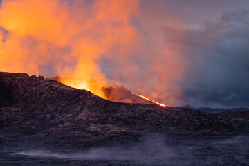Night volcanic eruption. Fresh hot lava, flames and poisonous gases going out from the crater.