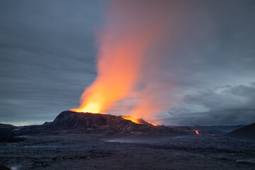 Fototapeta premium Night volcanic eruption. Fresh hot lava, flames and poisonous gases going out from the crater.