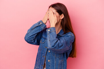 Young caucasian woman isolated on pink background afraid covering eyes with hands.