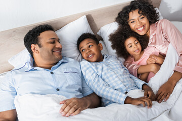 high angle view of cheerful african american family lying in bed in morning