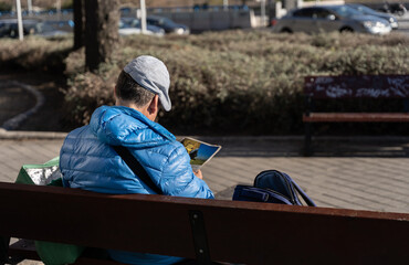 Man is reading a magazine sitting on a park
