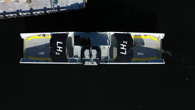Top-down view of ferry Hydra approaching Nesvik ferry pier in Rogaland Norway - Hydrogen powered ship with LH2 chemical symbol on top - Sunny day birdseye with no people or logo - Seagull passing