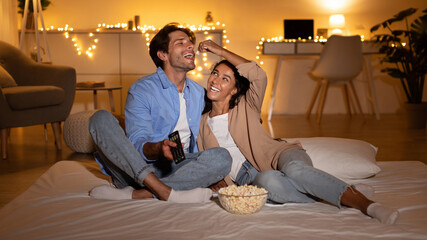 Couple Watching Television And Having Fun With Popcorn At Home