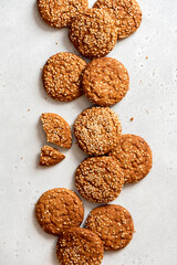 Homemade oatmeal cookies with sesame seeds on a gray concrete background top view. Tasty sweet breakfast, healthy food. Cookies background. Flat lay