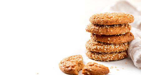 Homemade oatmeal cookies with sesame seeds on a white background. Tasty sweet breakfast, healthy food. Copy space. Banner