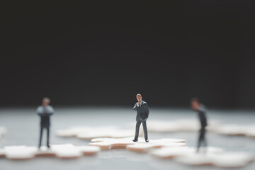 Miniature people : businessman standing in middle of businessman on jigsaw puzzle.