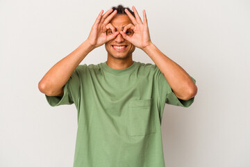 Young venezuelan man isolated on white background showing okay sign over eyes