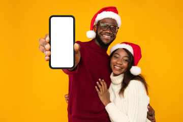 Black Couple In Santa Hats Showing Phone Screen, Yellow Background