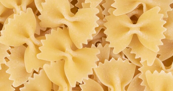 Rotation top view, closeup of uncooked farfalle pasta