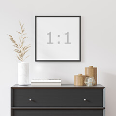 Empty square frame on white wall with black dresser, white vase and wood decor - close up image.