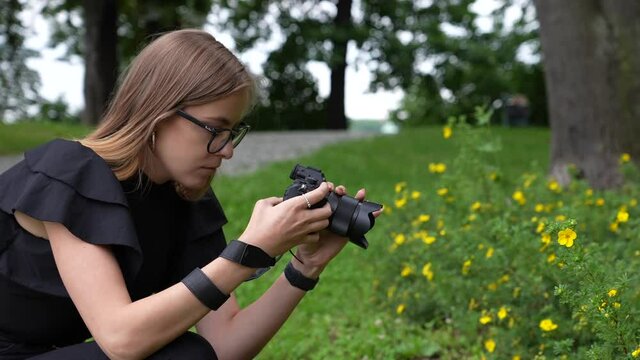 Profile of Young Female Photographer With Camera Taking Photo of Flowers in Park Full Frame Slow Motion