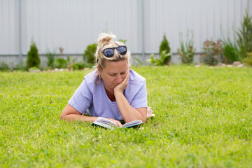 Woman lies on the grass and reads a book.