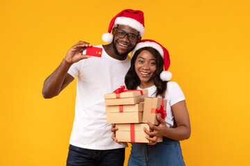 African Couple Showing Credit Card Holding Christmas Gifts, Yellow Background
