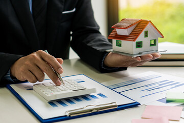 The sales representative offers a home purchase contract to purchase a house or apartment to customers at the desk in the idea office to buy or sell real estate.