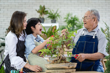 Fototapeta premium Happy family gardening together in the garden, grandfather grandson and woman taking care of nature