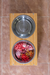 diet barf. raw dog food in aluminum plates on a wooden table in air plane and brown tiles background