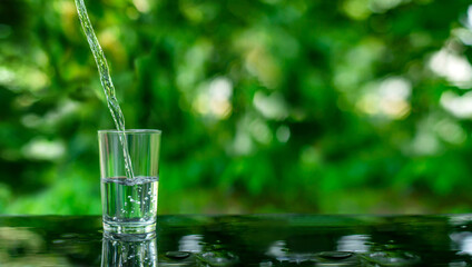 Water flows into a glass placed on a wooden bar.