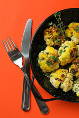 Concept of tasty food with baked cauliflower on orange background