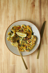 Concept of tasty food with baked cauliflower on wooden background