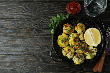 Concept of tasty food with baked cauliflower on wooden background