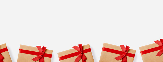 Fototapeta premium Christmas gifts and presents concept web banner with copy space. Gift boxes wrapped in craft paper with red bow on white background.