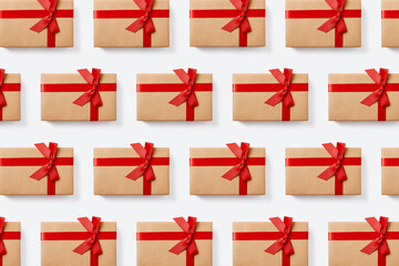 Repetitive pattern of holiday gift boxes wrapped in craft paper with red bow on white background....