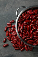 Pot with red beans on gray background