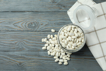 Jar with white beans on gray wooden background