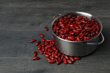 Pot with red beans on gray background
