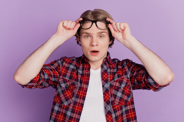 Portrait of excited shocked guy look camera open mouth take off specs on purple background