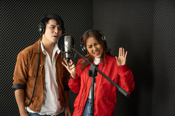 Asian couple singers in a recording studio using a studio microphone with passion in music recording studio